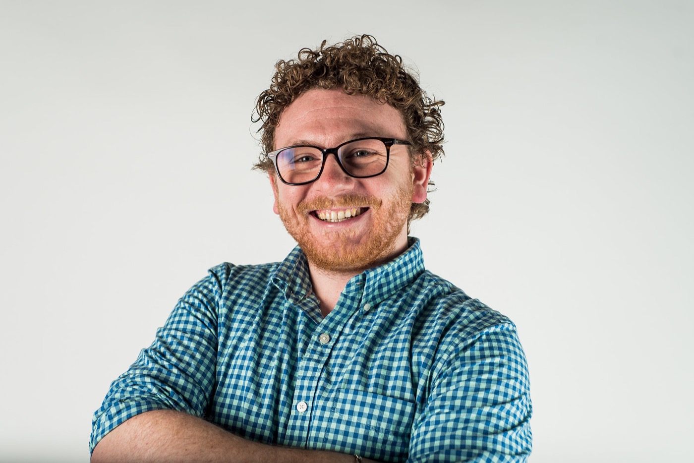 Portrait of Zachary Berardo smiling in a blue checkered shirt.